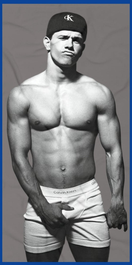 A black and white fashion photograph of Marky Mark wearing a black Calvin Klein cap and white Calvin Klein briefs on a premium beach towel by The Pink Rocket New Orleans a fay owned gift shop.