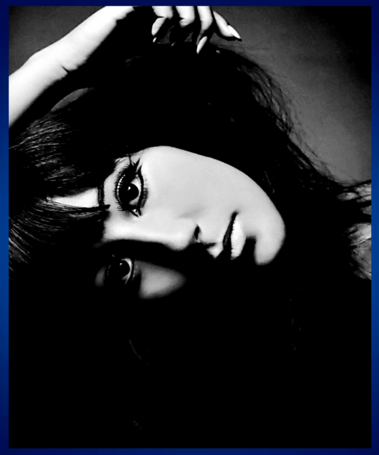 Black and white close-up portrait of Cher with dramatic shadowing, dark hair, and a hand near her head. Sold in The Pink Rocket New Orleans gay gift shop