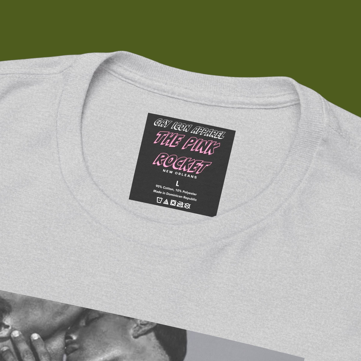 Brand label for A heather gray crewneck t-shirt featuring a black and white graphic print of a nude gay male couple embracing and kissing, with the text 'Art At Play' printed below the image. Designed and for sale in The Pink Rocket ew Olreans gay gift shop.