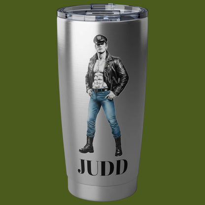 A brushed stainless steel tumbler with a clear lid, featuring a graphic of a muscular Tom of Finland man in a black leather jacket and blue jeans, peraonalized. with the name Judd For sale in The Pink Roket New Orleans gay gift shop.