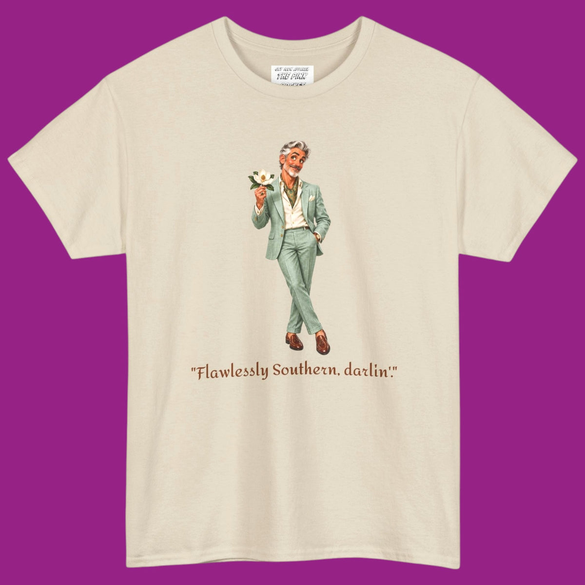 A cream short-sleeve t-shirt with a graphic of a gay man in a light green suit holding a flower, with the text "Flawlessly Southern, darlin'" printed below in brown letters. Designed and for sale in The Pink Rocket New Orleans gay gift shop.