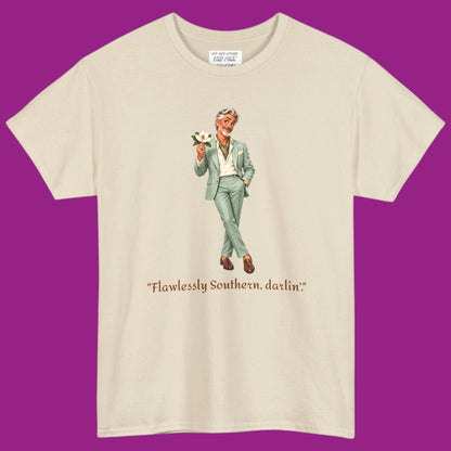A cream short-sleeve t-shirt with a graphic of a gay man in a light green suit holding a flower, with the text "Flawlessly Southern, darlin'" printed below in brown letters. Designed and for sale in The Pink Rocket New Orleans gay gift shop.