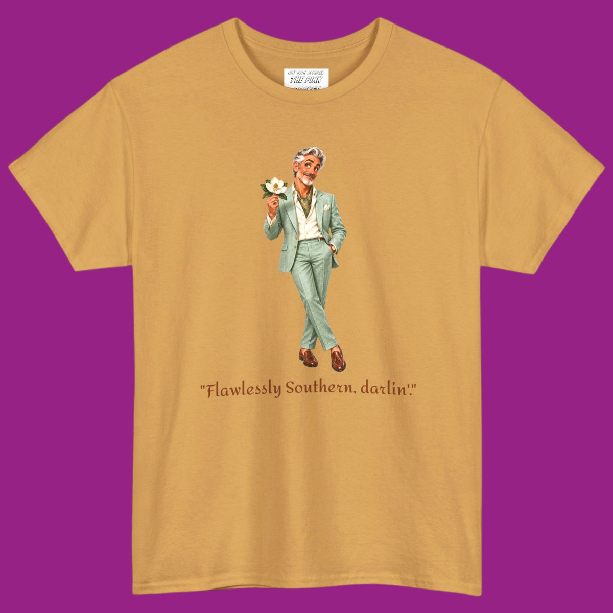 A gold short-sleeve t-shirt with a graphic of a gay man in a light green suit holding a flower, with the text "Flawlessly Southern, darlin'" printed below in brown letters. Designed and for sale in The Pink Rocket New Orleans gay gift shop.