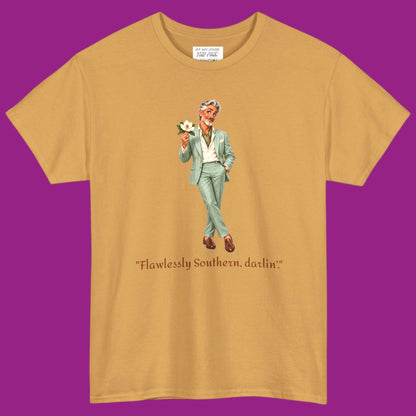 A gold short-sleeve t-shirt with a graphic of a gay man in a light green suit holding a flower, with the text "Flawlessly Southern, darlin'" printed below in brown letters. Designed and for sale in The Pink Rocket New Orleans gay gift shop.