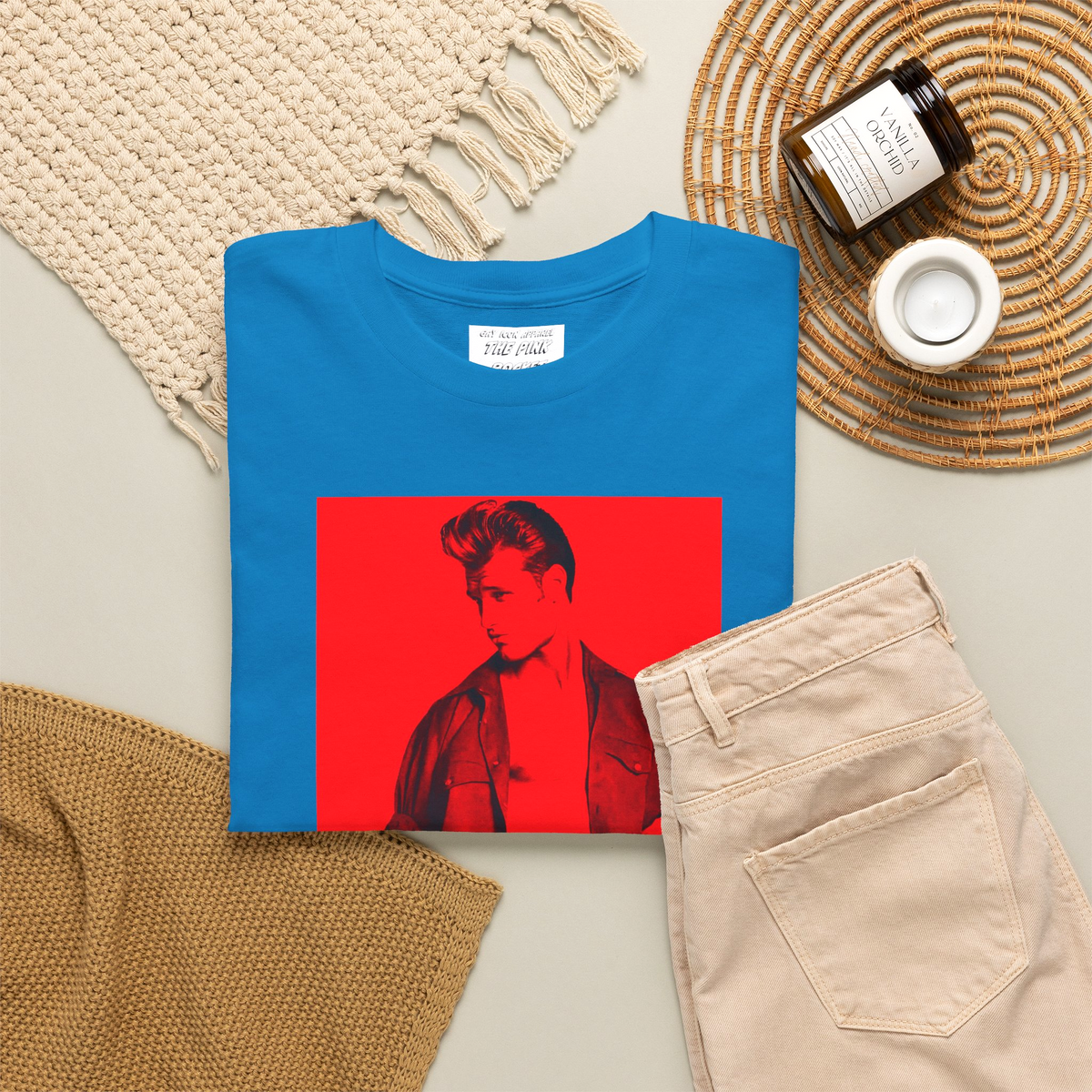 A folded baby blue short-sleeve t-shirt with a graphic print of a gay muscular man wearing a Versace shirt in a 1990s ad. Designed and for sale in The Pink Rocket New Orleans gay gift shop.