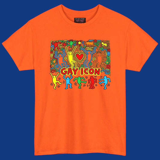 An orange short-sleeve crewneck t-shirt featuring a colorful graphic of a Keith Haring style 'Gay Icon' graphic, with a red heart and the words 'GAY ICON' in red, displayed against a solid blue background. Sold in The Pink Rocket New Orleans gay gift shop.