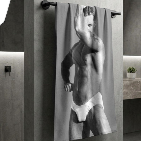 A custom beacjh towel hanging to dry in a modern bathroom with a photo of a hunky gay man in a bathing suit. Sexy and ready for the beach. For sale in The Pink Rocket New Orleans gay owned gift shop.
