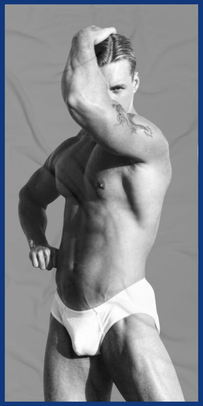 A custom  gray and white towel with a black-and-white photo of a hunky gay man in a bathing suit. Sexy and ready for the beach. For sale in The Pink Rocket New Orleans gay owned gift shop.