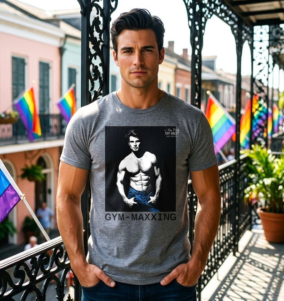 A heather gray short-sleeve t-shirt with a graphic print of a gay muscular man wearing blue pants, with the text 'GYM-MAXXING' printed below the graphic. Designed and for sale in The Pink Rocket New Orleans gay pride gift shop.