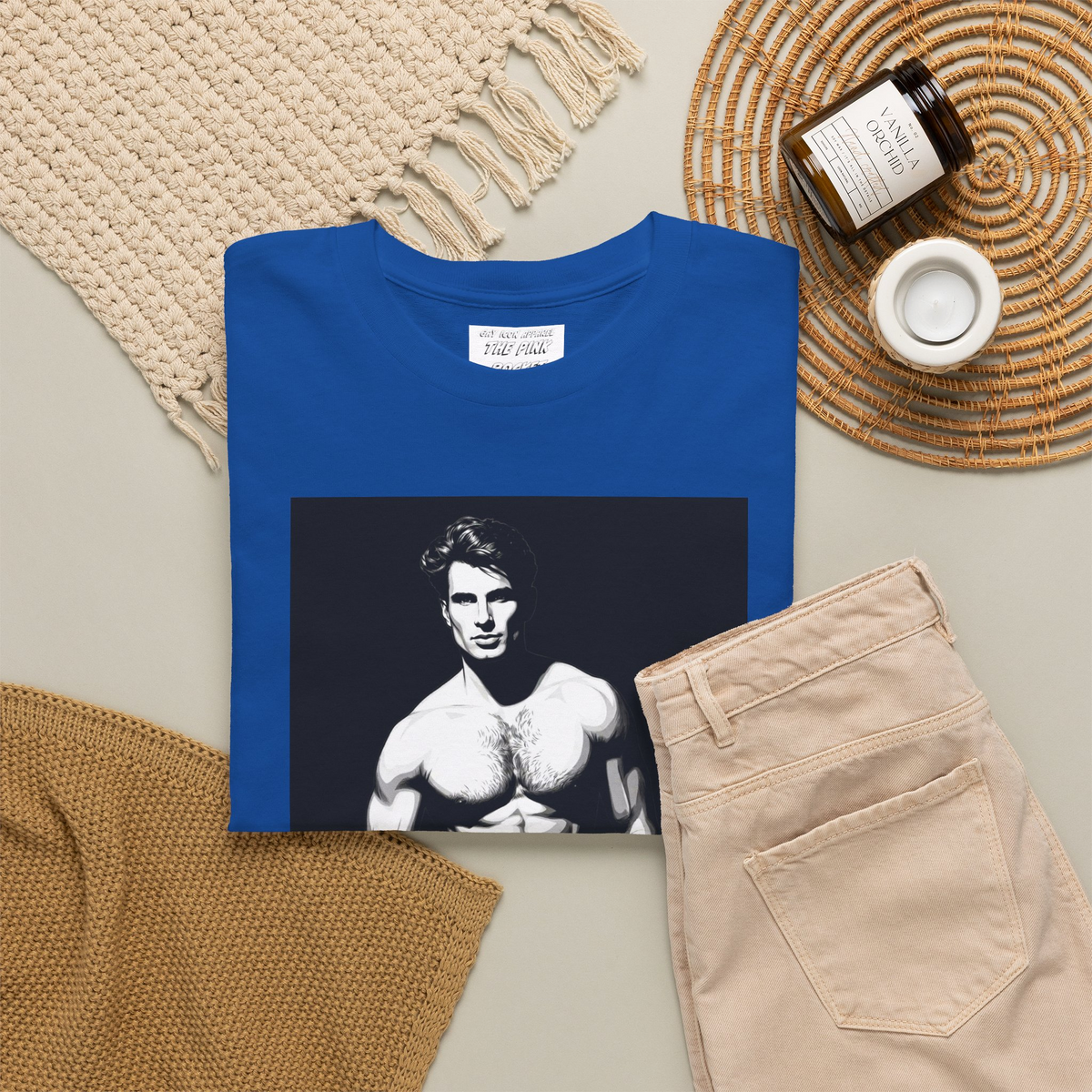A folded blue short-sleeve t-shirt with a graphic print of a gay muscular shirtless hunky man wearing blue pants, with the text 'GYM-MAXXING' printed below the graphic. Designed and for sale in The Pink Rocket New Orleans gay gift shop.