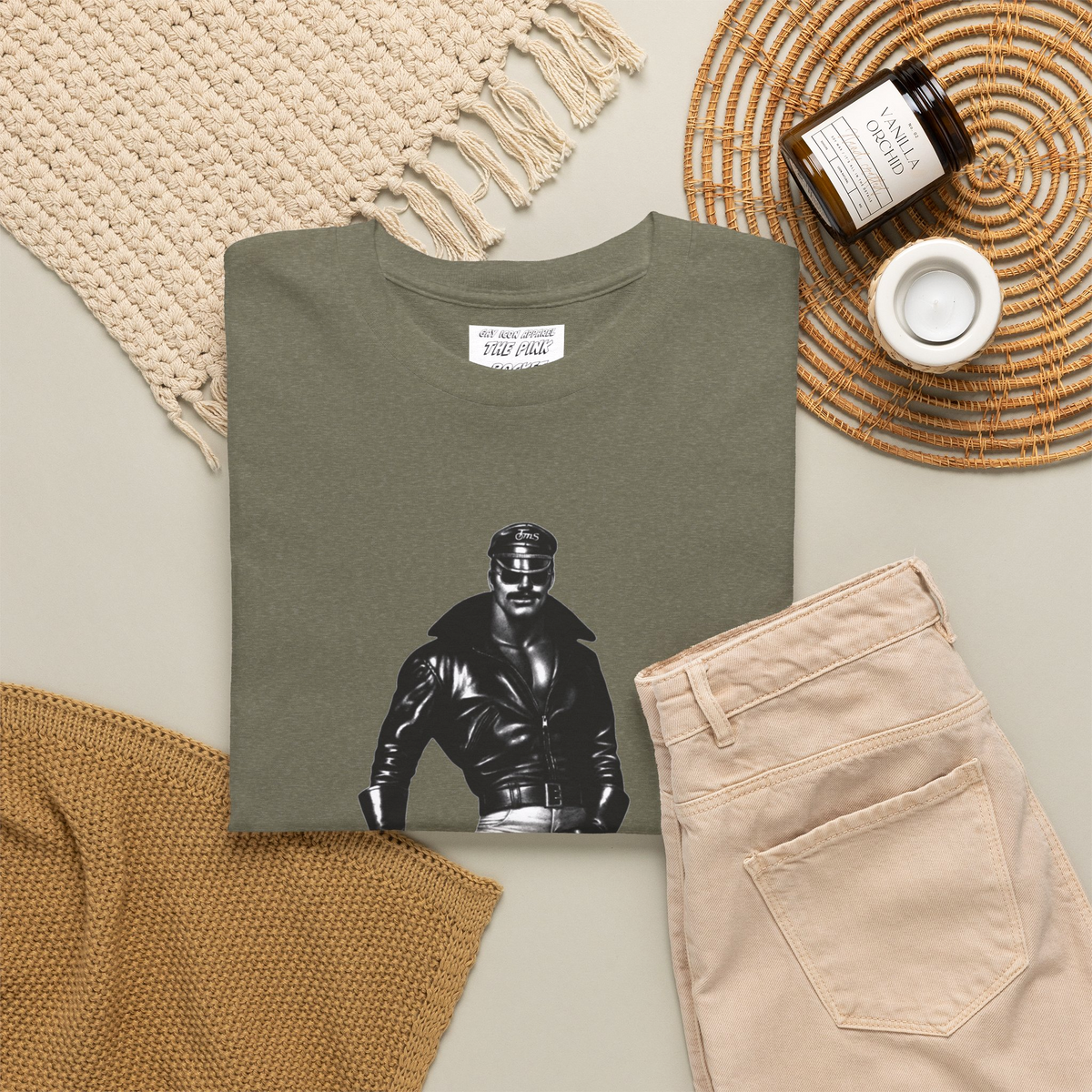 Folded heather green short-sleeve t-shirt featuring a Tom of Finland style black and white graphic image of a gay biker with a leather jacket and boots with his hand on his large bulge. Sold in The Pink Rocket New Orleans gay gift shop.