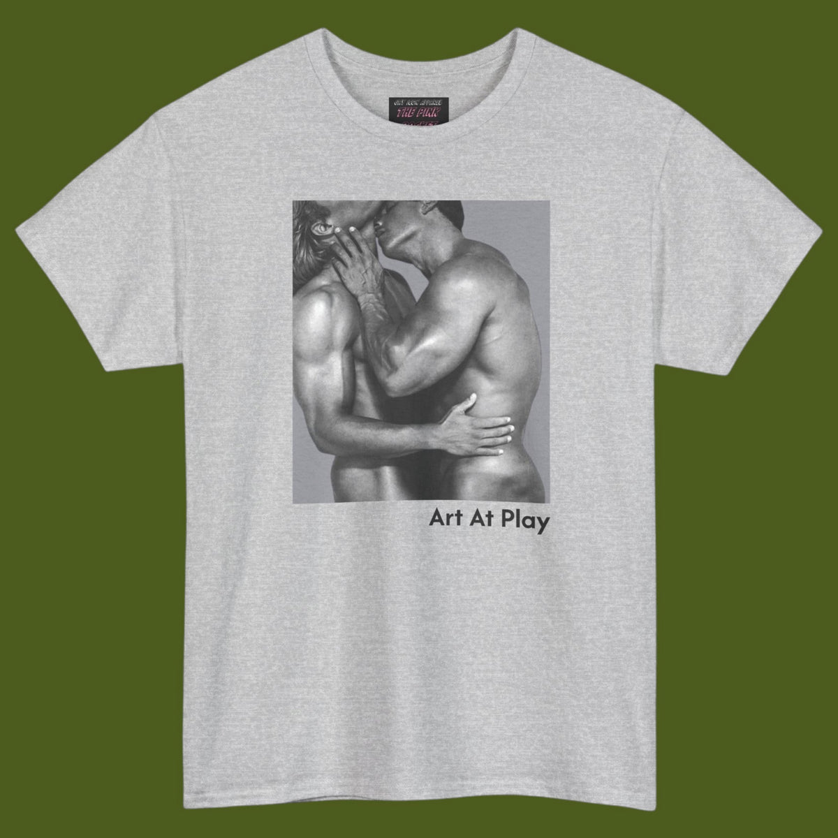 A light gray crewneck t-shirt featuring a black and white graphic print of a nude gay male couple embracing and kissing, with the text 'Art At Play' printed below the image. Designed and for sale in The Pink Rocket ew Olreans gay gift shop.