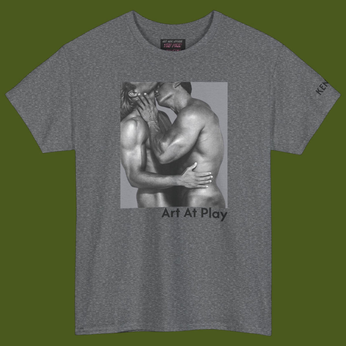 A heather gray crewneck t-shirt featuring a black and white graphic print of a nude gay male couple embracing and kissing, with the text 'Art At Play' printed below the image. Designed and for sale in The Pink Rocket ew Olreans gay gift shop.