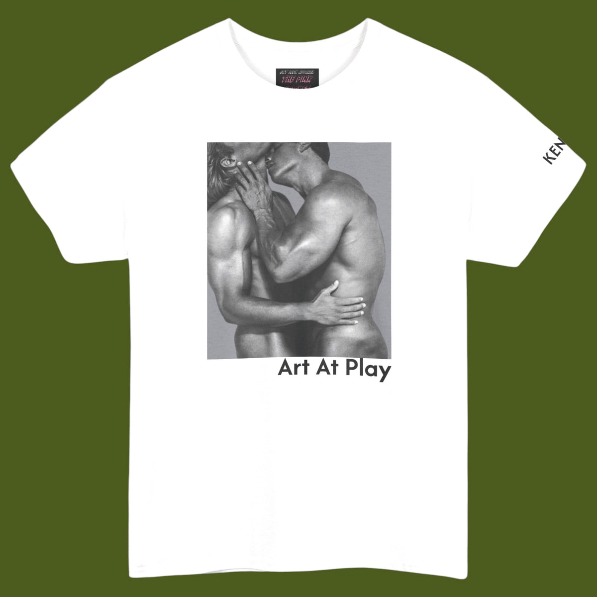 A white crewneck t-shirt featuring a black and white graphic print of a nude gay male couple embracing and kissing, with the text 'Art At Play' printed below the image. Designed and for sale in The Pink Rocket ew Olreans gay gift shop.