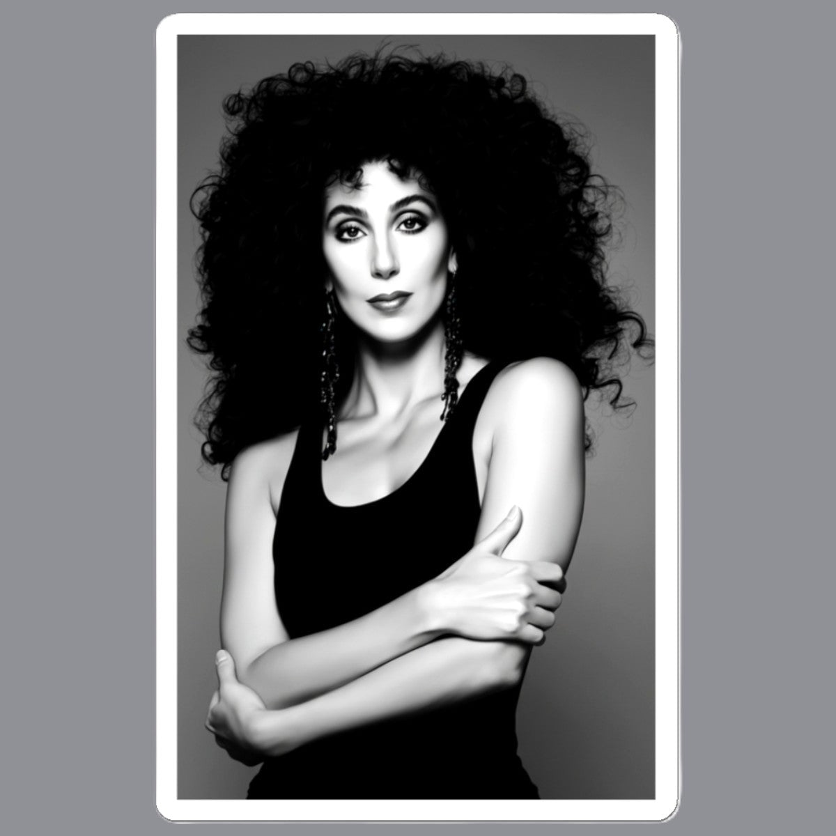A black and white portrait print of  Cher with voluminous curly hair, wearing a black tank top and dangling earrings, centered within a white border on a gray background. For sale in The Pink Rocket NOLA gay gift shop.